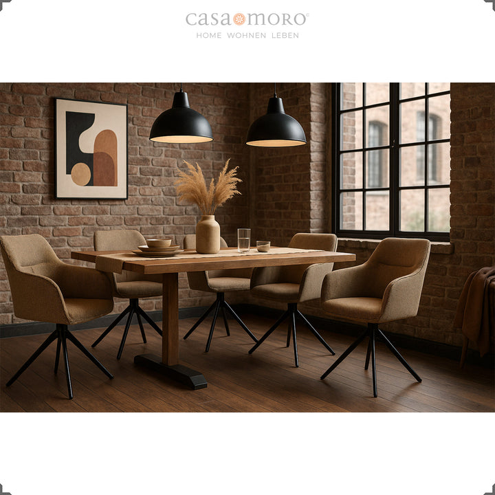 Four 360° swivel upholstered chairs with brown armrests at a wooden table in a modern dining room with a brick wall, black lamps and warm light