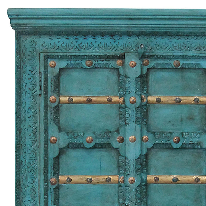 Close-up of turquoise carved ornaments, gold-coloured crosspieces and decorative fittings on the cabinet doors.