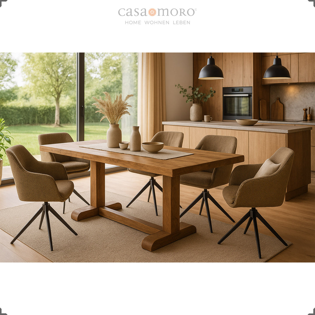 Four 360° swivel brown upholstered chairs with armrests around a wooden table in a modern kitchen with large windows and a view of the countryside