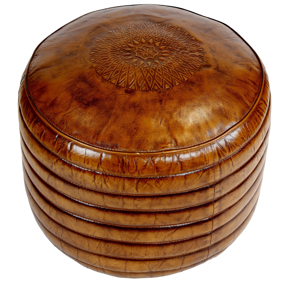 Round leather pouf in warm brown with fine surface embossing in a close-up view