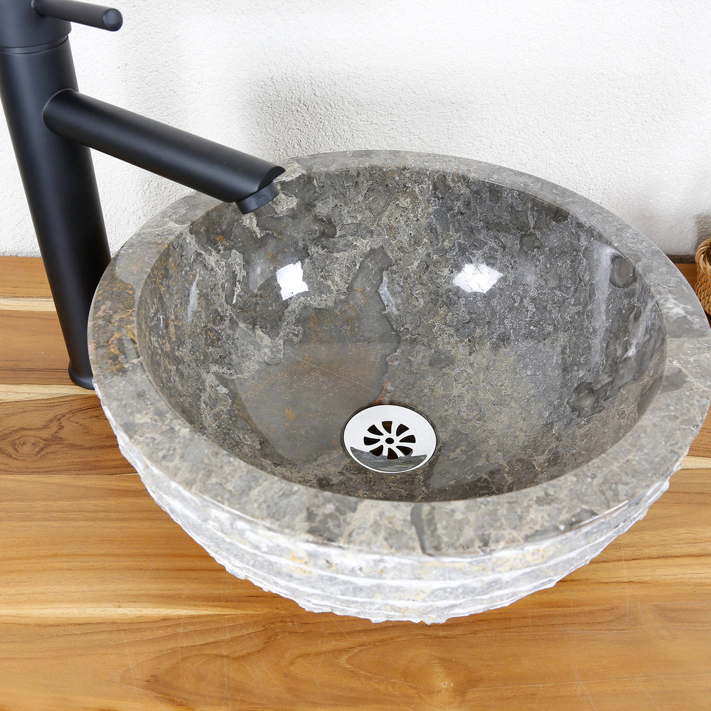 Round countertop washbasin made of natural stone with a polished inner surface and a structured outer edge on a wooden top