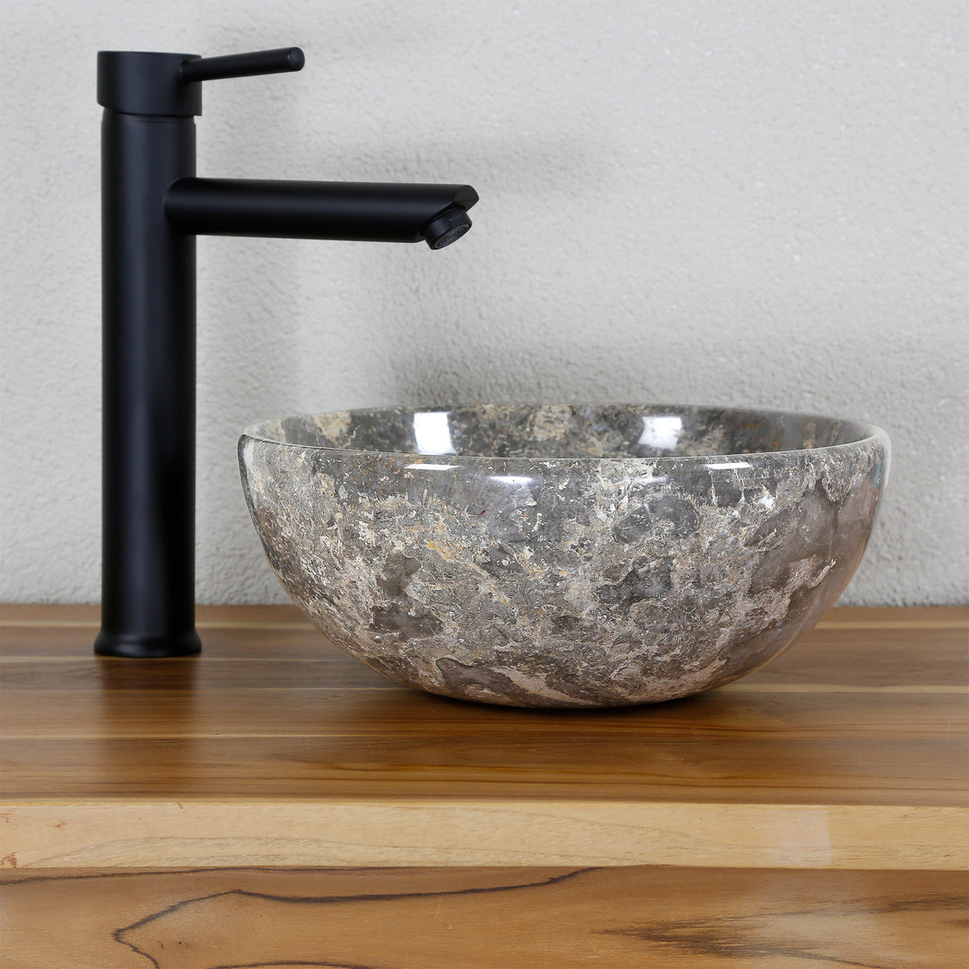 Round natural stone countertop washbasin with grey-brown grain on a wooden top, combined with a black stand-alone tap