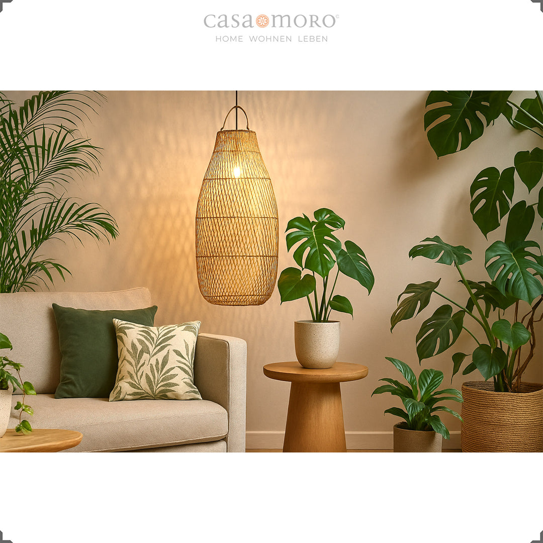 Large rattan ceiling lamp above sofa in living room with lots of green plants and warm light