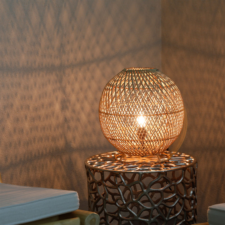 Round rattan lamp on a side table in the living room with a fine light pattern on the wall
