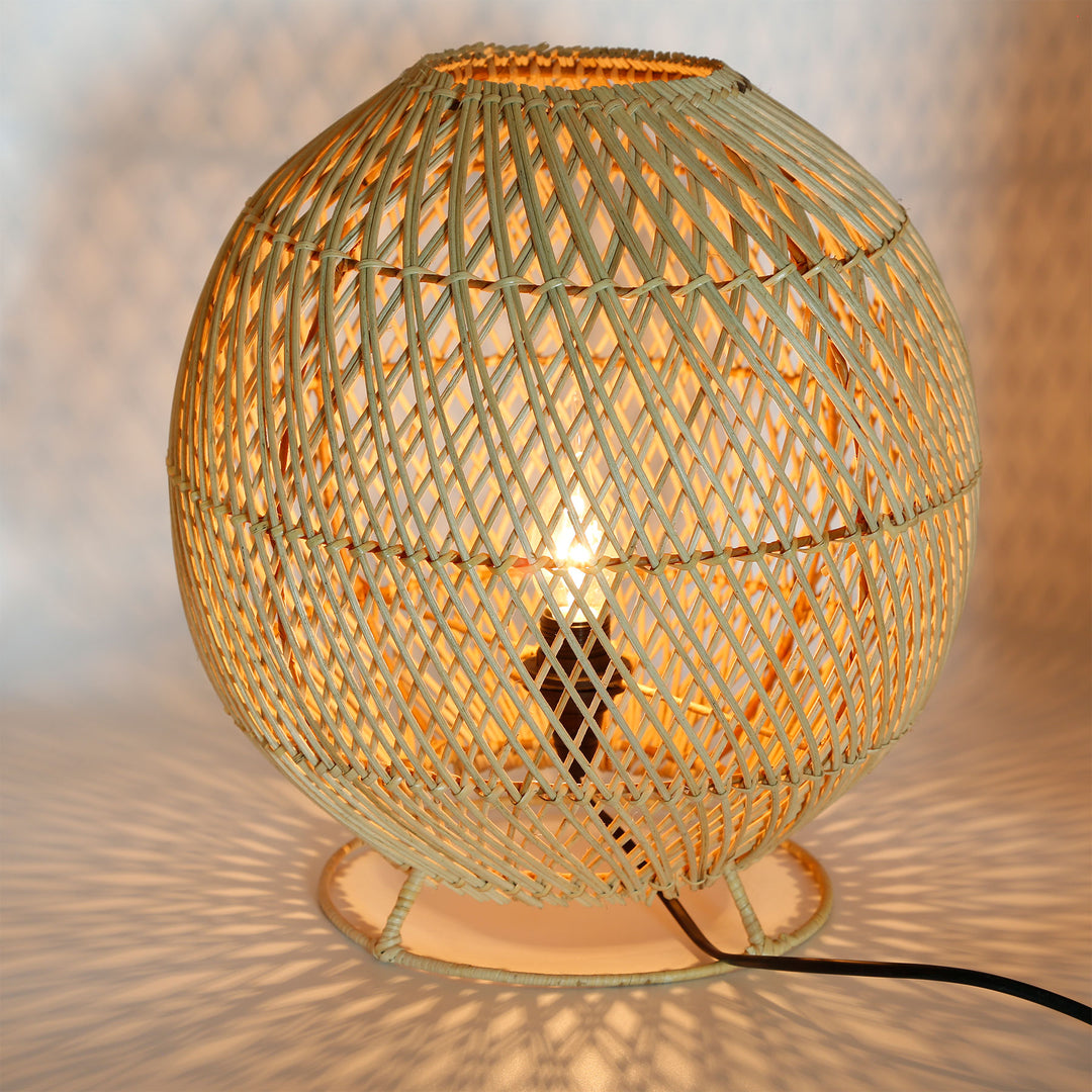 Round rattan floor lamp with a fine woven pattern and warm play of light on the wall and floor