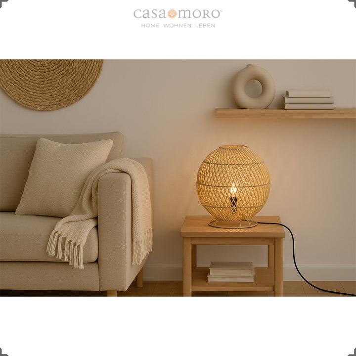 Round rattan table lamp on side table next to sofa, warm light and natural furnishings