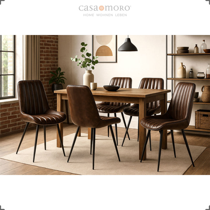 Antique brown leather chairs with black painted metal legs around a rectangular wooden table in modern dining room with brick wall