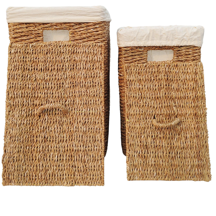 Two seagrass laundry baskets with capacities of 50 and 90 liters, featuring light-colored fabric inserts and lids that rest against the front with handles.