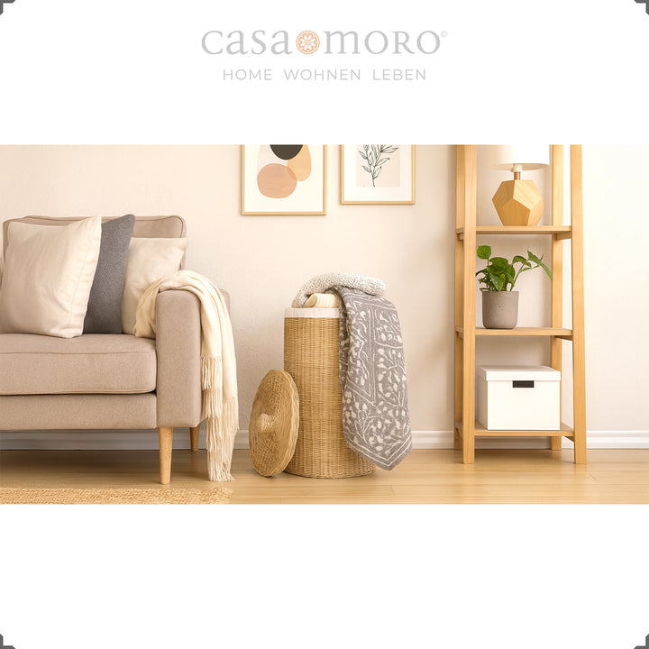 Rattan laundry basket in cozy living room, with blanket and pillows as storage basket