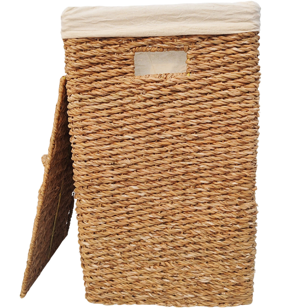 Rectangular laundry basket made of seagrass with a 90-liter capacity, a light-colored fabric liner, and a lid that rests against the side.