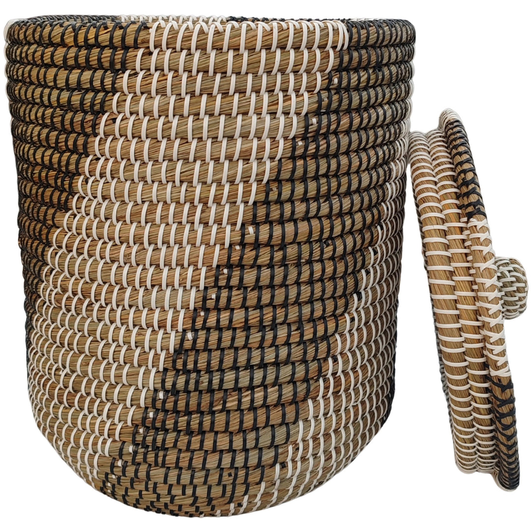 Laundry basket made of seagrass in natural, black, and white, with a capacity of approximately 40 liters and a lid that rests against the side.